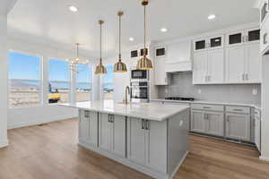 Kitchen with an island with double ovens, wood hood, and designer finishes