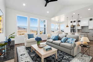 Living room featuring ceiling fan with notable chandelier, light hardwood / wood-style floors, and lofted ceiling