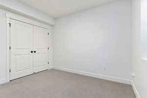 Unfurnished bedroom featuring light colored carpet and a closet