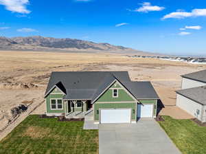 View of front of home featuring a mountain view, a front yard, and a garage