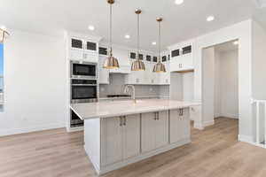 Kitchen with an island with double ovens, wood hood, and designer finishes