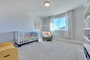 Bedroom with a crib and carpet flooring