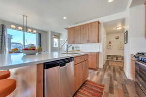 Kitchen featuring light hardwood / wood-style floors, sink, appliances with stainless steel finishes, backsplash, and hanging light fixtures