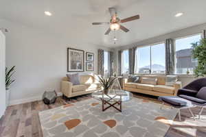 Living room featuring light wood-type flooring, a mountain view, and ceiling fan