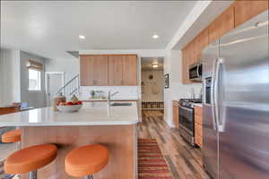 Kitchen with stainless steel appliances, backsplash, hardwood / wood-style floors, sink, and a kitchen island with sink