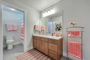 Bathroom with walk in shower, vanity, a textured ceiling, tile patterned flooring, and toilet