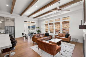 Living room featuring light hardwood / wood-style floors, ceiling fan, and beam ceiling