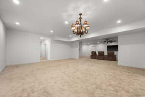 Unfurnished living room featuring light colored carpet and ceiling fan with notable chandelier