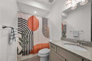 Bathroom with toilet, vanity, a shower with shower curtain, and tile patterned flooring