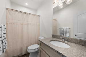 Bathroom featuring a shower with curtain, vanity, and toilet