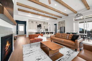 Living room featuring plenty of natural light, beam ceiling, and light hardwood / wood-style flooring