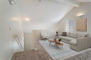 Living room with vaulted ceiling with beams and carpet floors