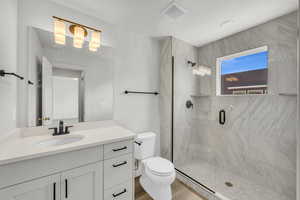 Bathroom with vanity, hardwood / wood-style flooring, toilet, and a shower with door