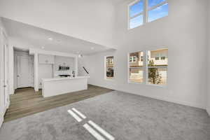 Unfurnished living room with a high ceiling and light wood-type flooring