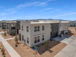 View of building exterior featuring a mountain view, a garage, and central AC unit