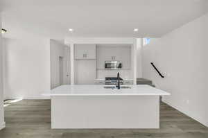 Kitchen featuring stainless steel appliances, sink, a kitchen island with sink, and hardwood / wood-style floors