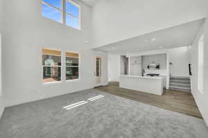 Unfurnished living room with a high ceiling, sink, hardwood / wood-style floors, and plenty of natural light