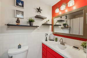 Bathroom with vanity, toilet, and tile walls