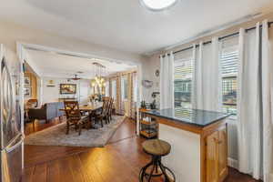 Kitchen with stainless steel refrigerator, ceiling fan, a breakfast bar area, decorative light fixtures, and dark wood-type flooring