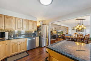 Kitchen with light brown cabinets, dark hardwood / wood-style flooring, appliances with stainless steel finishes, and tasteful backsplash