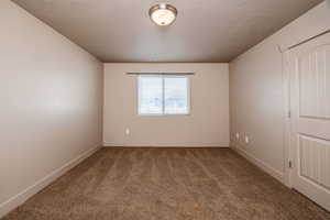 Empty room with carpet flooring and a textured ceiling