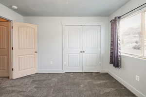 Unfurnished bedroom featuring carpet floors, a textured ceiling, and a closet