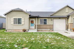 Single story home with a garage and a front lawn