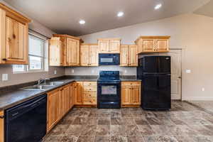 Kitchen with black appliances, light brown cabinets, sink, and vaulted ceiling