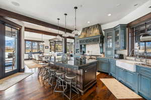 Kitchen with decorative light fixtures, a kitchen island, dark wood-type flooring, and sink