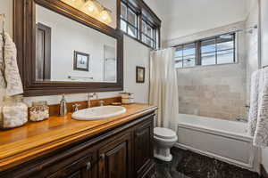 Full bathroom featuring vanity, plenty of natural light, toilet, and shower / tub combo