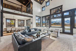 Living room featuring carpet, high vaulted ceiling, and a notable chandelier