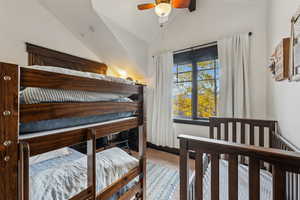 Bedroom featuring carpet, ceiling fan, and high vaulted ceiling