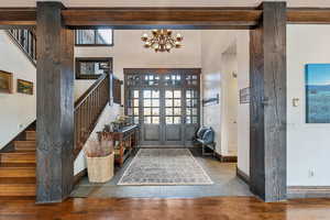 Entryway with a chandelier, beam ceiling, dark wood-type flooring, and french doors