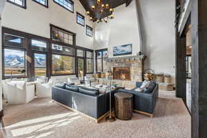 Carpeted living room featuring a fireplace, a chandelier, high vaulted ceiling, and beamed ceiling