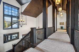 Corridor featuring carpet, wood ceiling, high vaulted ceiling, and an inviting chandelier