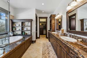 Bathroom with tile patterned floors, vanity, and a bath