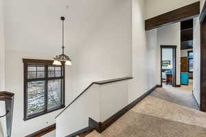 Hallway featuring carpet floors, high vaulted ceiling, and a chandelier