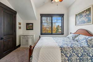 Bedroom with ceiling fan, carpet floors, and lofted ceiling