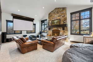 Cinema featuring a fireplace, light colored carpet, and lofted ceiling