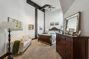 Bedroom with beamed ceiling, ceiling fan, light carpet, and a high ceiling