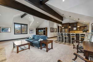 Carpeted living room with beam ceiling and high vaulted ceiling