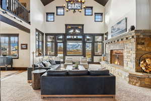 Carpeted living room featuring a fireplace, an inviting chandelier, and high vaulted ceiling