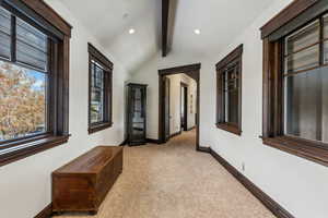 Hall with vaulted ceiling with beams and light colored carpet