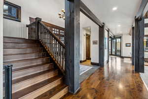 Stairs with wood-type flooring and an inviting chandelier