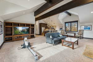 Carpeted living room featuring vaulted ceiling with beams