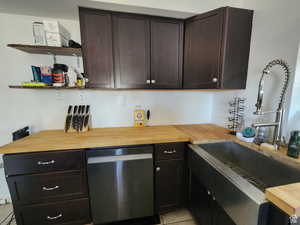 Kitchen featuring dishwasher, tile, sink, and wood counters