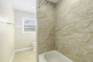 Bathroom with tiled shower / bath and toilet