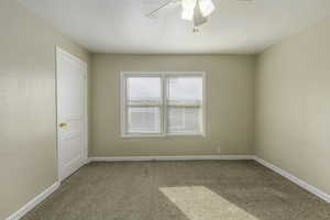 Carpeted spare room with a textured ceiling and ceiling fan