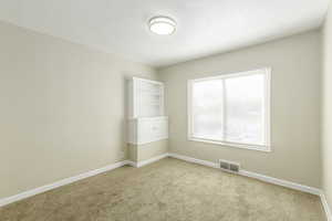 Unfurnished room with a textured ceiling and light colored carpet