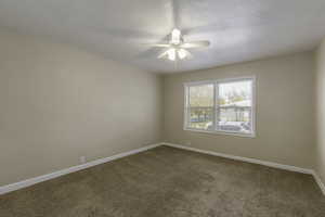 Carpeted spare room with ceiling fan and a textured ceiling